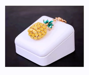 Macro detail of pineapple keychain with yellow cat-eye stones and green crystal leaves