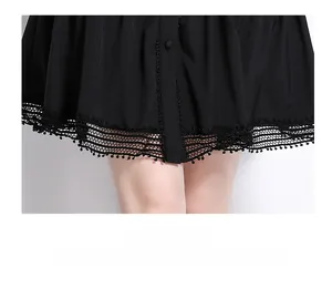 Detail of elegant black dress hem with lace splicing, pom-pom trim and buttons