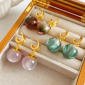 Detailed shot of three pairs of spherical resin drop earrings in a wooden jewelry box