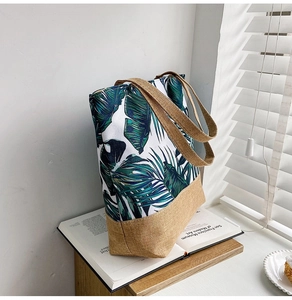 Detail of canvas tote bag featuring green leaf print and natural brown burlap handles