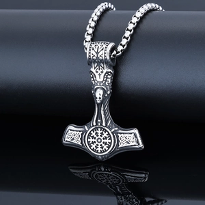 Macro detail of antique silver Mjolnir pendant with Viking carvings on black background