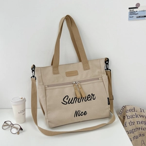 Detail of beige canvas tote bag with Summer Nice embroidery and leather logo patch