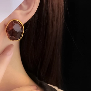 Detail of vintage geometric gold twisted earring with an irregular brown resin stone
