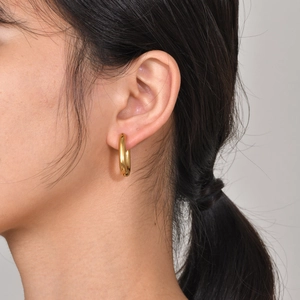 Close-up of a minimalist gold octagonal hoop earring worn on a model's earlobe