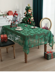 Detail of green lace Christmas tablecloth with festive reindeer and snowflake patterns