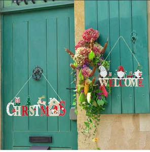 Dettaglio di targa natalizia in legno con motivi di Babbo Natale e cervi su porta verde