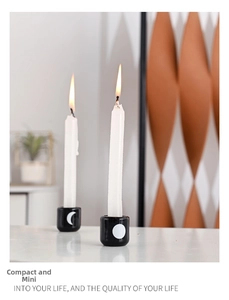 Detail of black ceramic candle holders featuring moon patterns in a cozy home setting