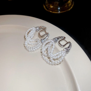 Detail of silver horseshoe earrings with zircon inlay and multi-layer pearl tassels