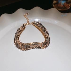 Detailed view of a gold leopard print bracelet with dark rhinestones and lobster clasp