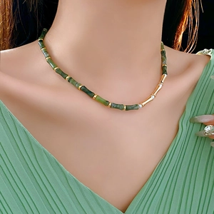 Detail of green bamboo style jade and gold beads necklace worn by a fashion model