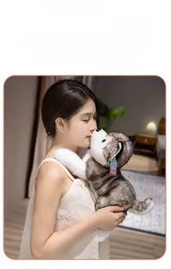 Close-up of a soft grey and white husky plush toy being held by a model in a bedroom