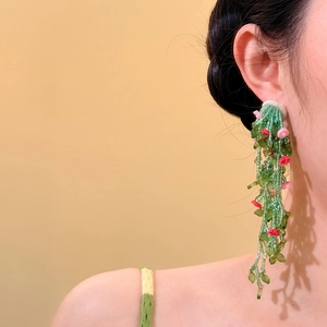 Detail shot of elegant green beaded tassel earrings with pink flowers on a model