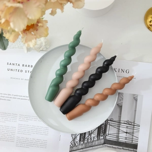 Spiral twisted soy wax candles in four colors displayed on a plate over a magazine