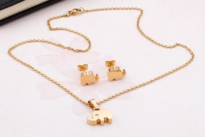 Detailansicht eines goldenen Elefanten-Schmucksets mit Kette und Ohrsteckern auf Rosa