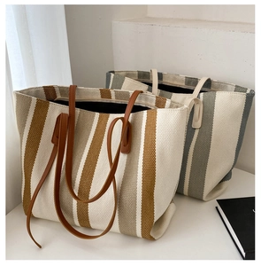 Close-up of dual-tone striped canvas tote bags featuring premium leather handles and large capacity