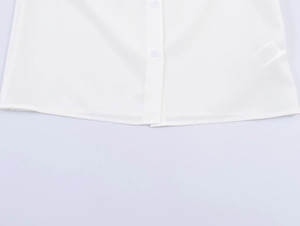 Close-up of the clean hem and white buttons on a sleeveless cotton summer blouse