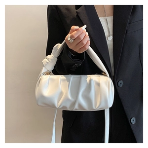 Close-up of white ruched cloud bag with knotted handle detail on black blazer