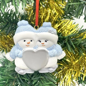 Hanging snowman couple ornament in blue and white on a festive green Christmas tree