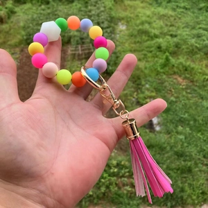 Dettaglio del bracciale portachiavi in perline di silicone con nappa rosa e fibbia oro