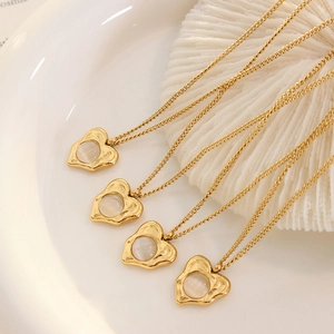 Gold heart pendant necklaces with white cat eye stones on decorative coral base