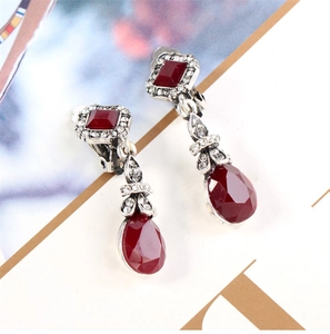 Detailed view of bohemian teardrop earrings with deep red gemstones and silver accents