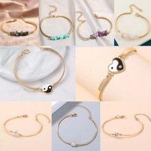 Vue détaillée de divers bracelets en chaîne dorée avec pendentifs en cristal coloré