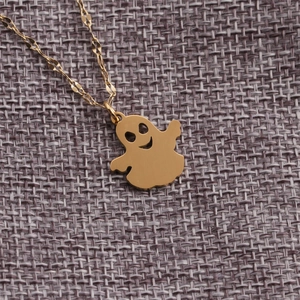 Collana con ciondolo a fantasma in acciaio inossidabile dorato su sfondo in tessuto grigio