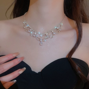 Dettaglio della collana dorata a più strati con pendente a goccia e strass scintillanti