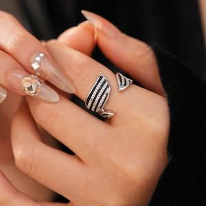 Close-up of a vintage geometric open ring with black lines and inlaid white zircons