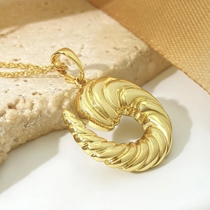 Chic twisted croissant pendant gold necklace for women on minimalist white background