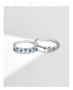 Close-up of S925 silver rings with alternating blue and white crystals in soft light