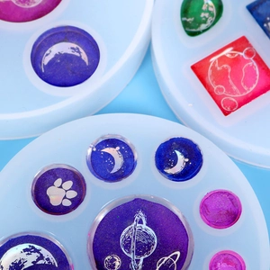 Vue macro de breloques planètes colorées en résine et de moules en silicone