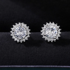 Macro shot of silver sunflower stud earrings with zircon center on black velvet