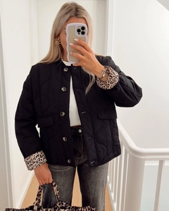 Close-up of quilted black jacket featuring leopard print lining and large round buttons