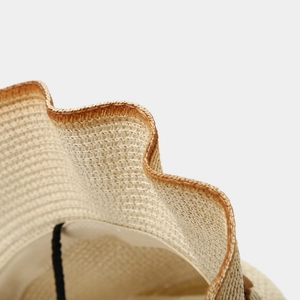 Gros plan du chapeau de paille montrant la texture et le bord ondulé marron élégant