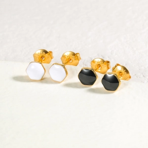 Gros plan sur des boucles d'oreilles hexagonales émaillées noires et blanches dorées