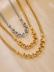 Detailed view of gold and silver mixed pig nose chain necklaces on beige fabric
