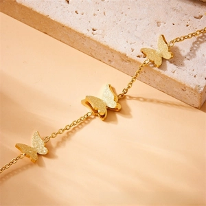 Detail of rose gold butterfly layered bracelet with frosted finish on natural stone