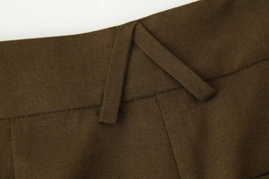 Détail du pantalon tissé marron foncé montrant les passants de ceinture et la texture