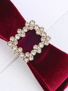 Macro shot of a square rhinestone buckle on deep red velvet ribbon hair accessory