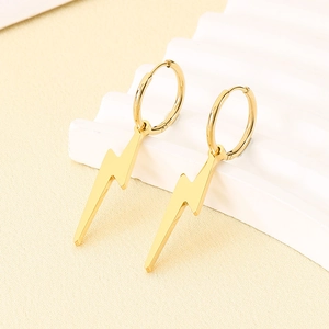Macro detail of polished gold lightning bolt earrings on a textured backdrop