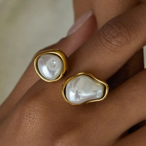 Bague ouverte élégante en acier doré 18K avec deux perles baroques sur la main du mannequin