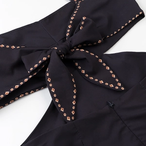 Detail of black dress featuring a back bow tie and orange geometric pattern borders