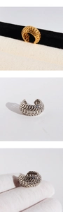 Detail of woven chain ear cuff in gold and silver finish on textured fabric