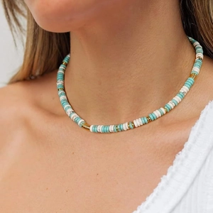 Detail of bohemian beaded necklace featuring turquoise, white and gold stones on model