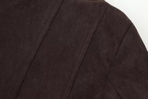 Gros plan détaillé montrant les coutures sur le tissu en daim marron de la veste