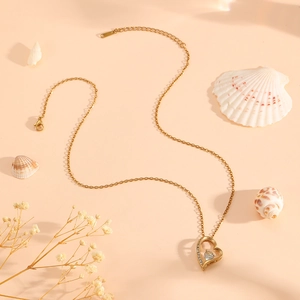 Elegant gold titanium heart necklace with zircon stone on a beach themed background