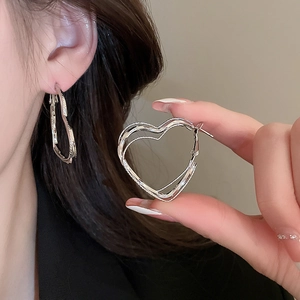 Close-up of heart-shaped multi-layered silver hoop earrings worn on the ear detail