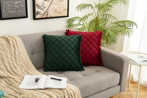 Detail of velvet throw pillows with diamond quilted patterns and pom-pom trim accents