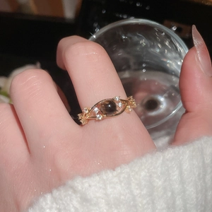 Close-up of vintage golden ring with brown cat eye stone and zircon accents on model